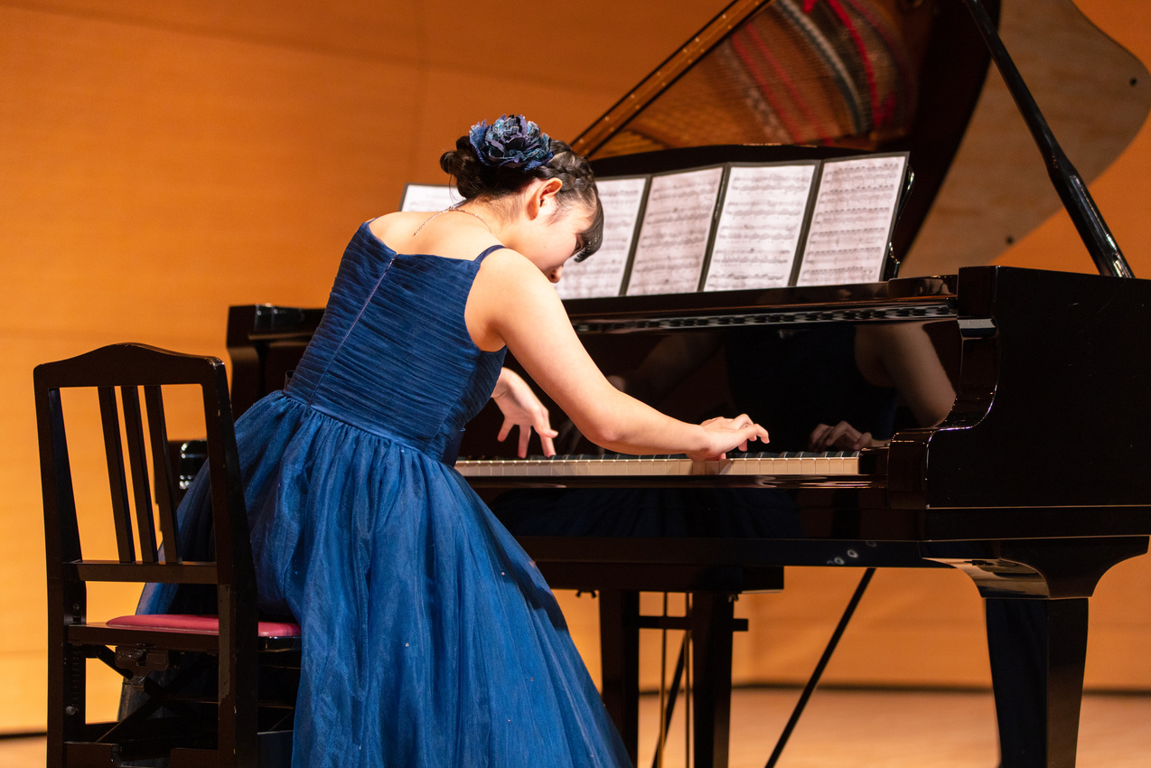 Teenage girl playing piano at concert hall